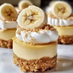 Mini Banana Pudding Cheesecakes with vanilla wafer crust, creamy banana cheesecake filling, topped with banana pudding, fresh banana slices, whipped cream and a vanilla wafer.