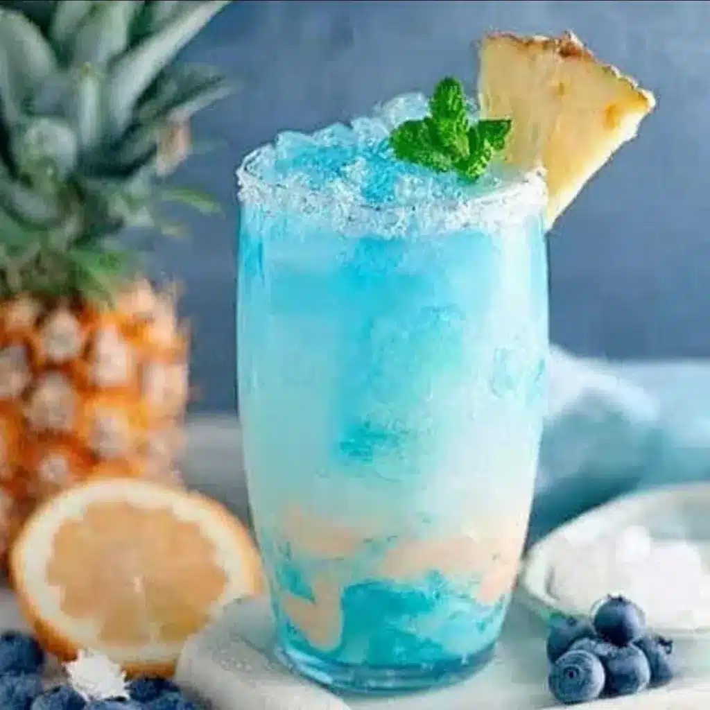 Magical Mermaid Punch in glass. Non-alcoholic tropical drink with fruit garnish.