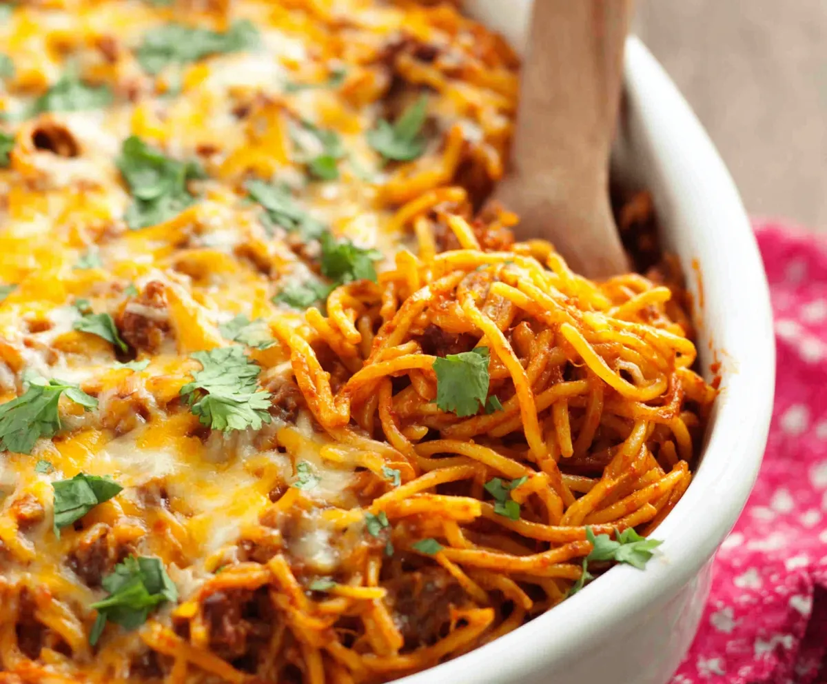 A close-up shot showcases a delicious Southern Spaghetti Bake, bubbling with cheese and a rich tomato sauce.