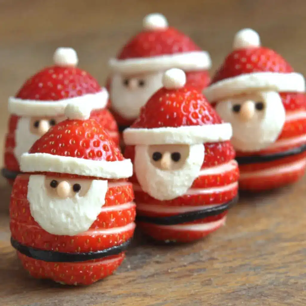 A close-up shows festive Strawberry Santa Treats with whipped cream and chocolate chip faces, perfect for a holiday dessert.